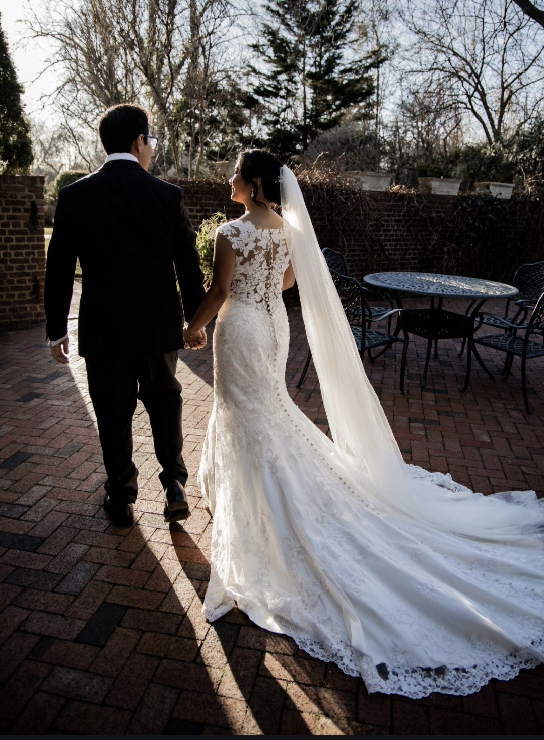 Bride in lace mermaid gown with cathedral veil on brick patio